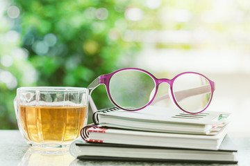 Eyeglasses on spiral notebooks with cup of tea