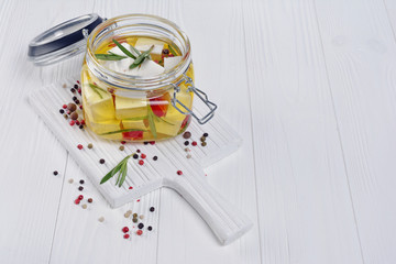 Marinated feta cheese with olive oil and spice of red chili pepper and rosemary in glass jar