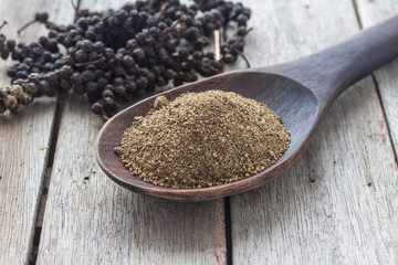 allspice in wooden ladle on wood background.