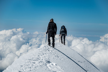 Alpinists on Aiguille de Bionnassay summit - extremely narrow snow ridge above clouds, Mont Blanc...