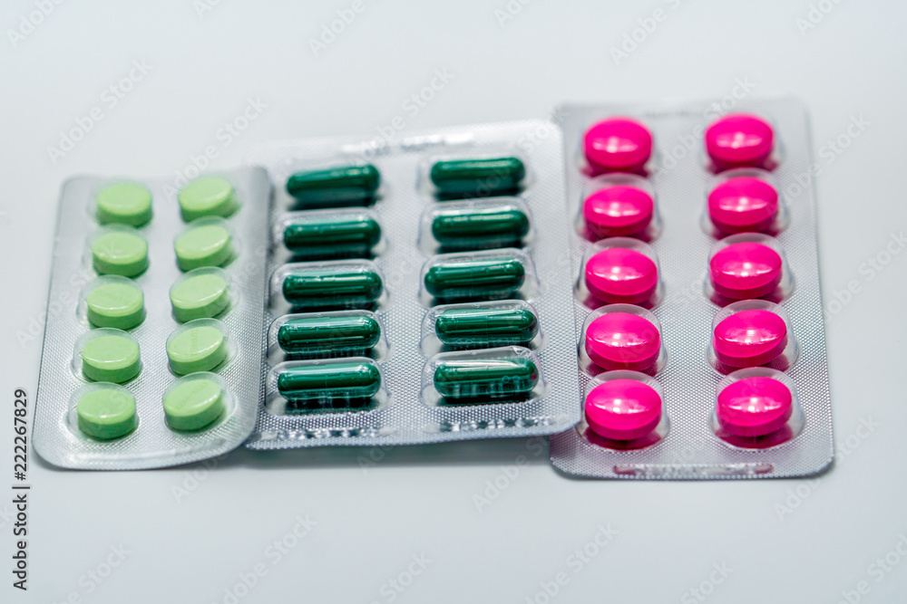 Sticker pink tablets and green capsule and green tablets in blister pack on white background. painkiller med