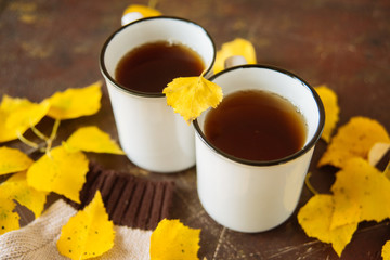 two white cups of tea in the yellow leaves, the concept of cosiness, warmth and autumnal sadness