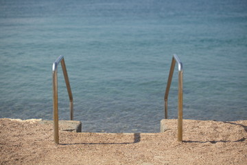staircase with metal railings for the descent into the sea from the pier beach