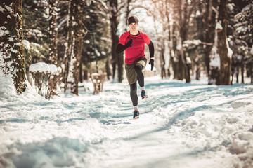 Young man running at winter in park