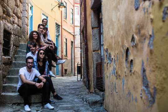 Fototapeta Company of young people sitting on a narrow street of the old European city.