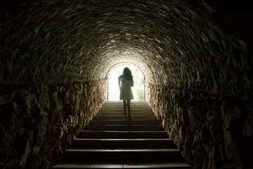 Girl walking throug dark tunnel into light