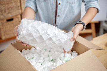 Close-up of woman unpacking her online order, she receiving beautiful vase