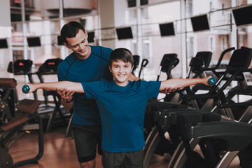 Fototapeta na wymiar Young Father and Son Doing Exercises in Sport Club