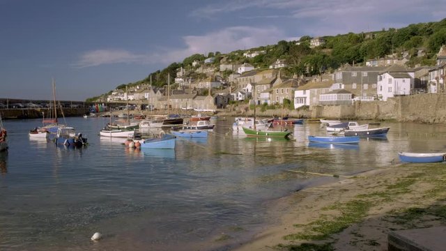 Static low angle clip of harbour of Mousehole in Cornwall with colorful fishing boats moored