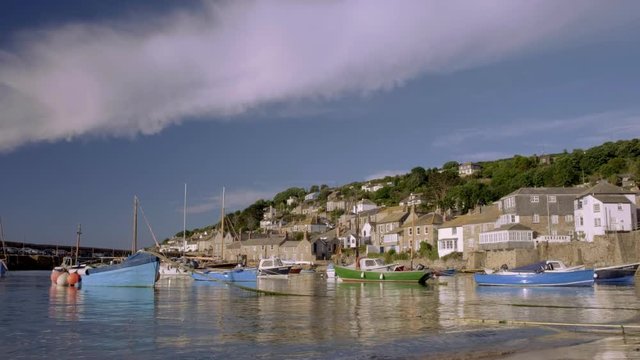  Mousehole in Cornwall with colorful fishing boats moored and dramatic cloud