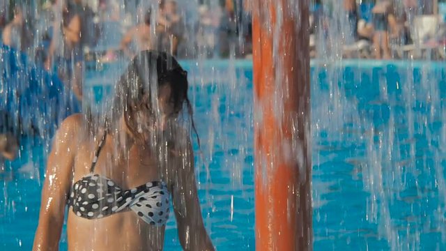 The girl in the water park. Happy girl under a fountain in a water park.