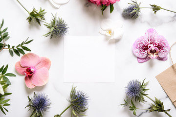 Marble desk with pink and blue flowers, postcard, invitation card with copy space for your text. Flat lay, top view. Woman's day or mother's day mockup.