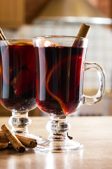 Mulled wine in glass with spice and fruit on wooden table.