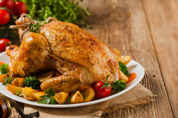 Roast chicken whole. Served on a plate with vegetables and baked potatoes. © gkrphoto