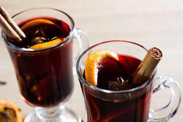 Mulled wine in glass with spice and fruit on wooden table.