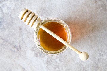 Honey jar with wooden spoon on grunge background