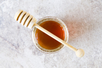 Obraz na płótnie Canvas Honey jar with wooden spoon on grunge background