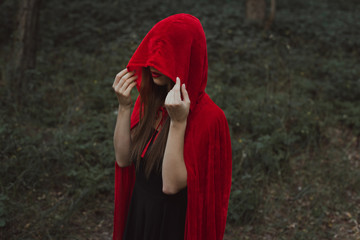 mystic girl in red cloak and hood in forest
