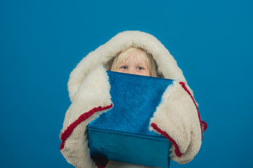 Obraz premium Boxing day before holiday celebration party. boxing day of santa kid in coat holding blue box.