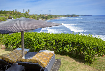 Fototapeta premium Bali, Indonesia. Beds under the beach umbrella overlooking the sea on the edge of the cliff