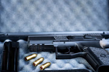 Close up view of bullets and handgun. Small black pistol next to a 9 mm bullets and a magazine. Shallow depth of field.