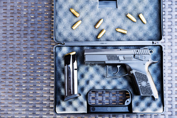 Top view of bullets and handgun. Small black pistol next to a 9 mm bullets and a magazine.