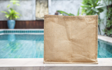 Design jute bag over blurred swimming pool background, ecological product concept