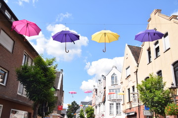 Bunte aufgespannte Regenschirme über einer Einkaufsstrasse