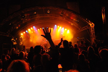 Fototapeta na wymiar Feiernde und tanzende Menschenmenge vor einer Konzertbühne bei Nacht