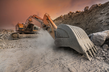 Large excavator extracting stone in a dust cloud in a desert