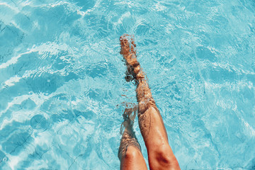 beautiful woman legs splashing in the pool - obrazy, fototapety, plakaty