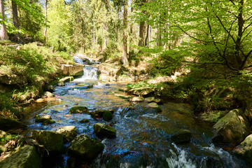 a clear river is flowing through natural cascades in the forest