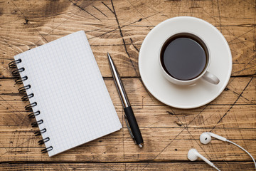 Notepad for text and Cup of coffee with copy space on wooden background. Education and office concept.