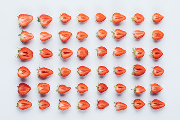 top view of composition of ripe halved strawberries on white surface