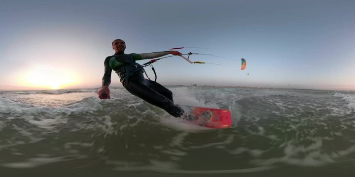 A man on a red wakeboard is engaged in kitesurfing and is holding a selfie stick