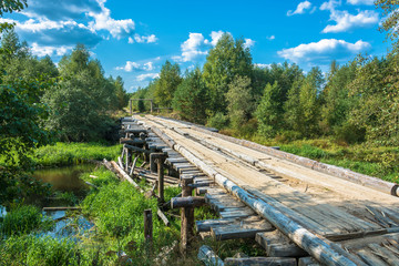 Fototapeta na wymiar A wooden bridge across a small river.