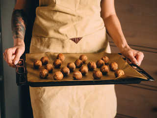 Raw frozen meat balls on baking sheet with paper
