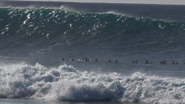 Surfers surfing massive waves. Big swell with huge waves hitting the shoreline
