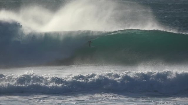 Surfers surfing massive waves. Big swell with huge waves hitting the shoreline