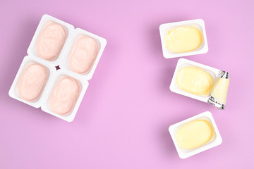 Plastic cup with tasty yogurt on lilac background. Top view. Space for text or design.