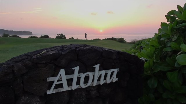 Aloha sign with sunrise in the background. sign on black lava rock