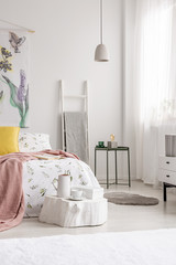 A cozy fresh bedroom interior in white with a bed dressed in sheets, pillows and blanket. Real photo.