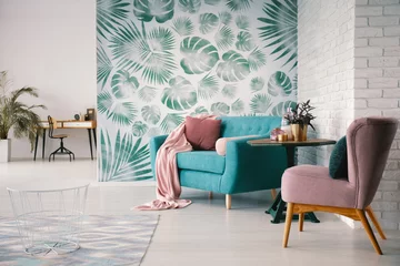 Foto op Canvas Chair and turquoise sofa in green living room interior with leaves wallpaper and table. Real photo © Photographee.eu