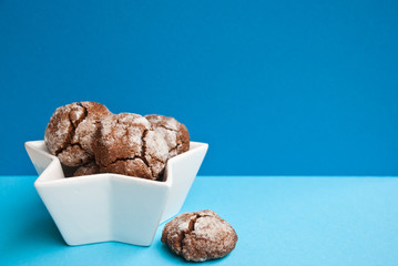 Chocolate cookies in white bowl on blue background. Food Card with space for text.