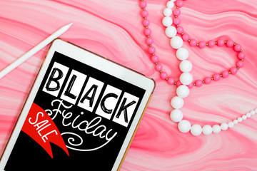 Black friday sale Minimal flat lay with tablet, beads and pen on pink marble background. top view