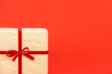 Christmas gift box on red background. White recycled / reused wrapping paper with red ribbon. Empty blank copy space for text.
