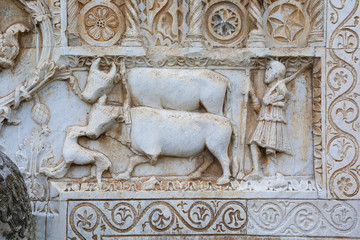 Farmer and oxen on medieval bas-relief, from the facade of Saint Peter church, Spoleto, Italy.