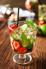 Glass of fresh strawberry mojito on wooden table