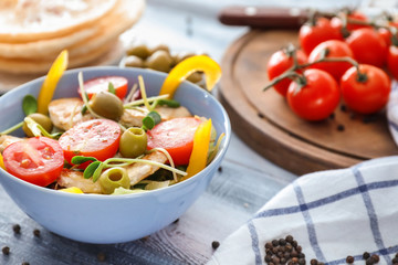 Bowl with tasty chicken salad on wooden table