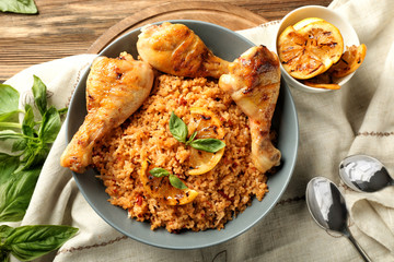 Tasty boiled rice with chicken drumsticks in bowl on table